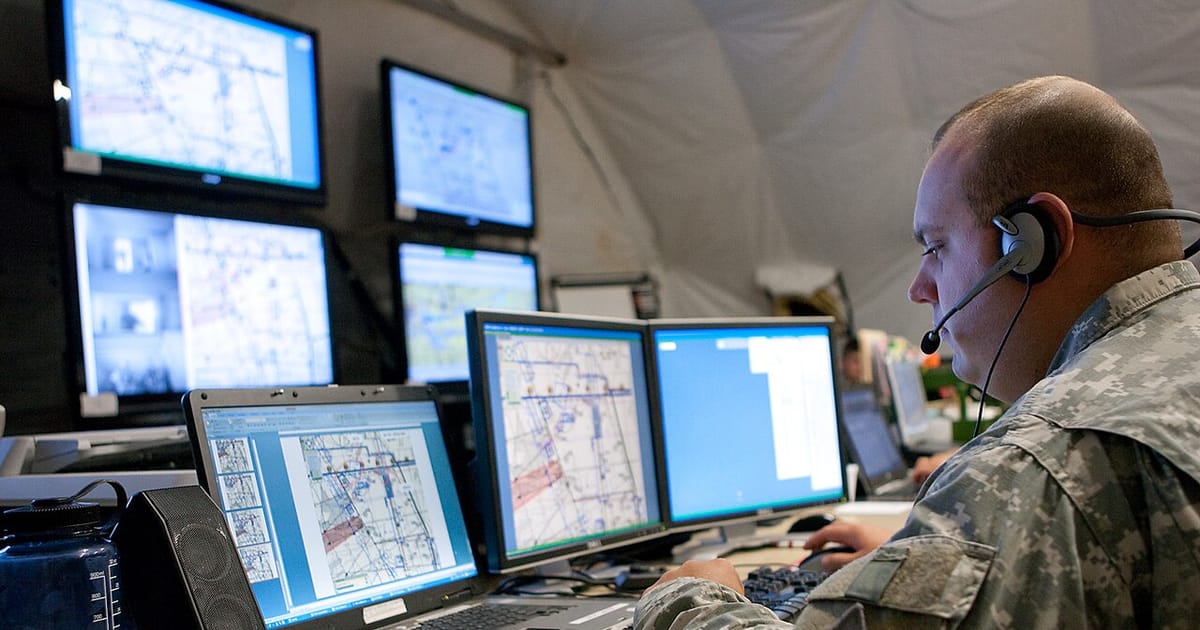 A soldier monitoring multiple screens at a tactical operations center